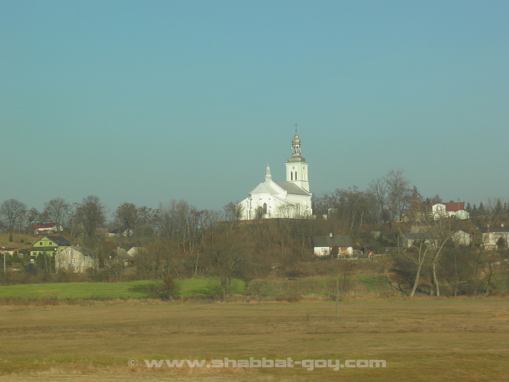 Le village de Chełmno nad Nerem (Chelmno sur le Ner) vu depuis l'autoroute A2. Au centre, l'église où étaient enfermés les déportés dans l'attente de leur tragique destin.  Le musée se trouve sur la gauche de l'église (toit gris) dans les arbres, où se trouvait à l'origine le manoir
